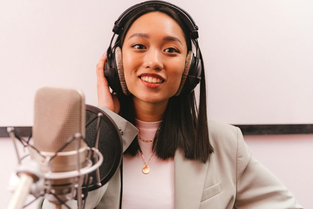 年輕女性在錄音室中錄製 Podcast 節目，配戴耳機與專業麥克風錄音