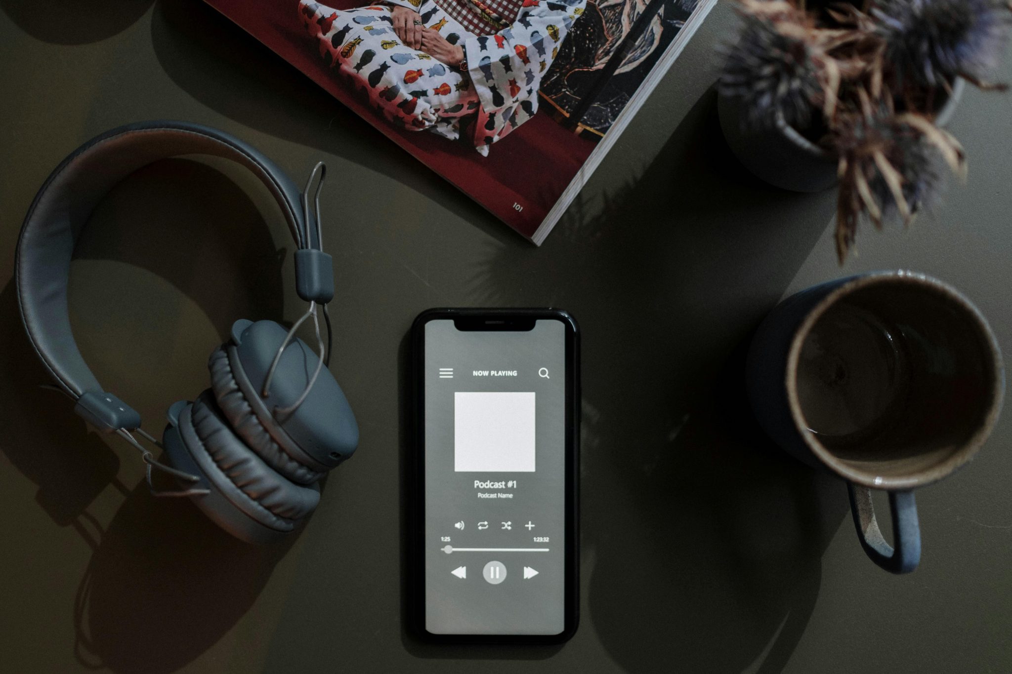手機播放 Podcast 節目搭配耳機與咖啡，呈現聲音頻率與日常結合的聆聽場景