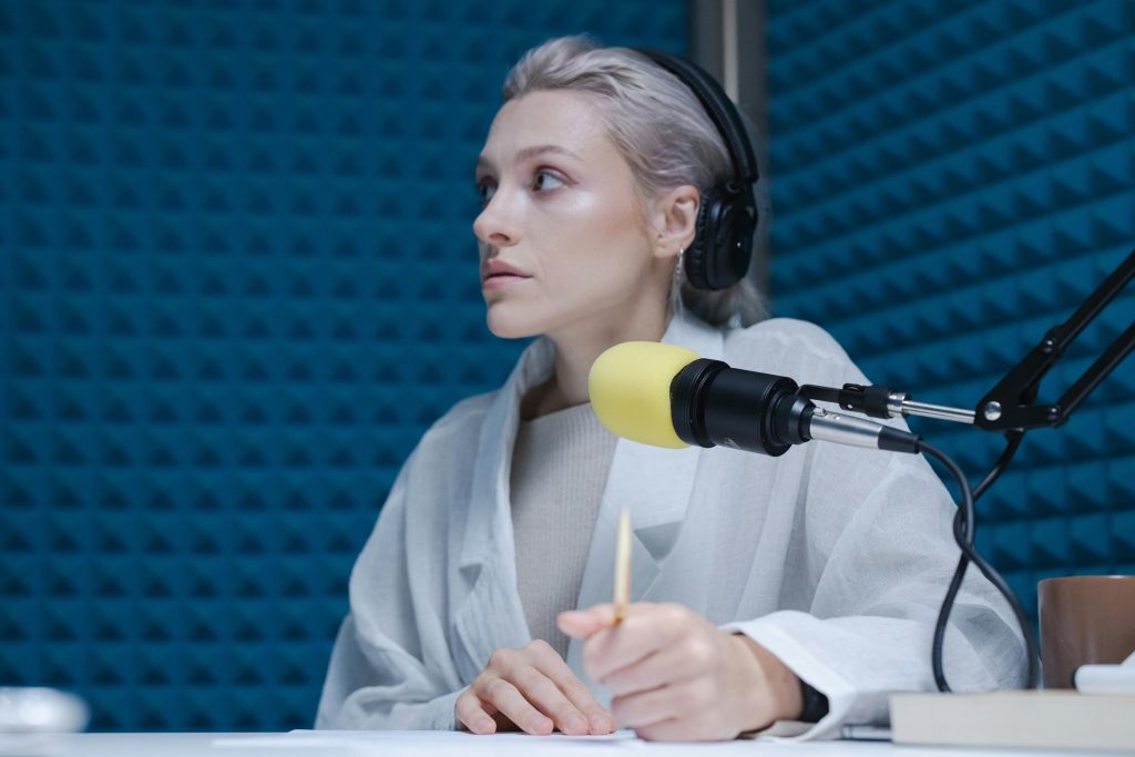 女性 Podcaster 在專業錄音室使用耳機與麥克風進行錄音