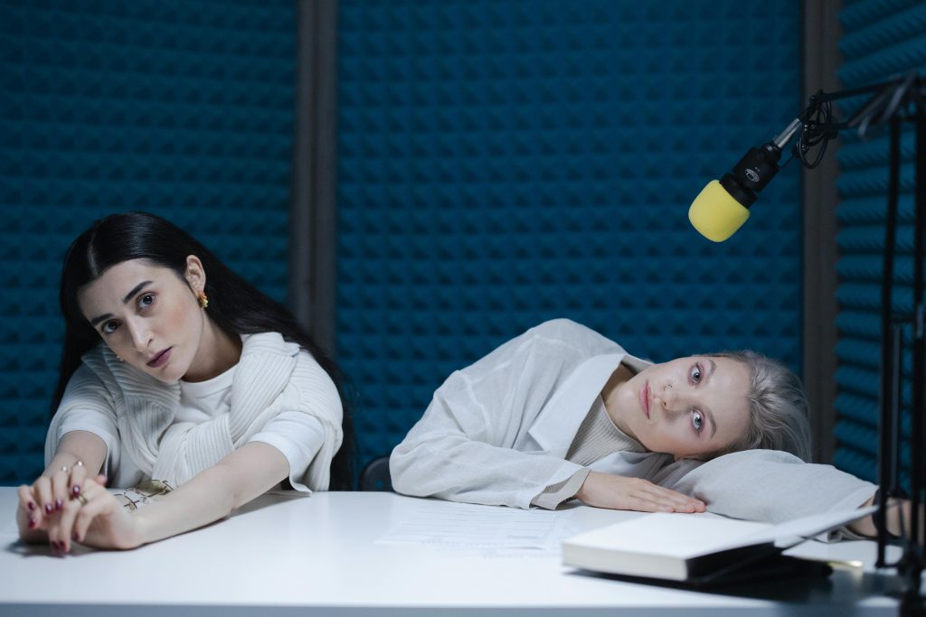 兩位 Podcast 主持人在錄音室中錄音後呈現疲憊放鬆的狀態
