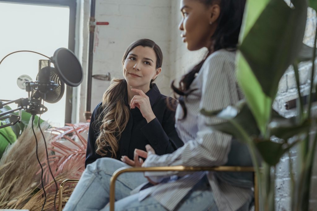 兩位女性在自然光環境中使用 Podcast 麥克風對談 