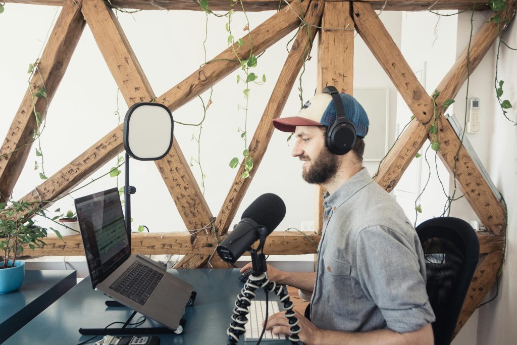 男性創作者在自然光下錄製 Podcast，使用筆電與 USB 麥克風進行節目製作