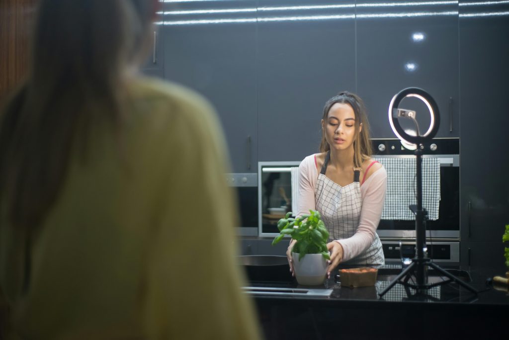 女性創作者在廚房拍攝影音內容，使用補光燈與手機錄影設備
