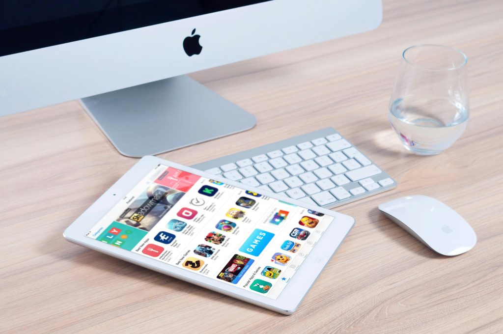 iPad 展示應用程式商店畫面，搭配桌面電腦與滑鼠