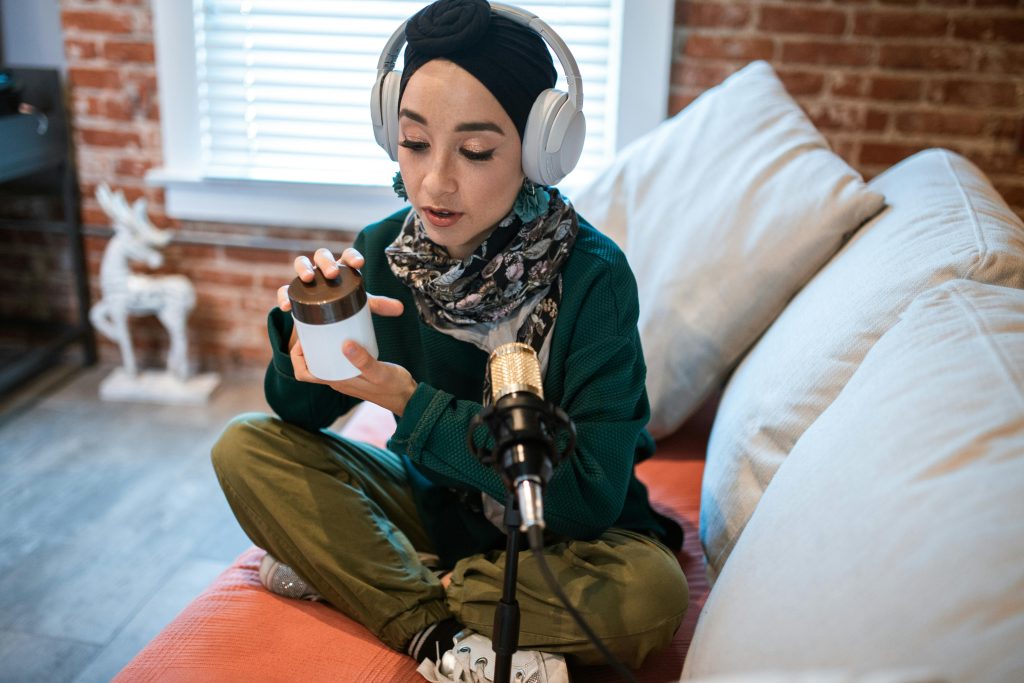 女性 Podcaster 在居家空間使用金色麥克風進行錄音