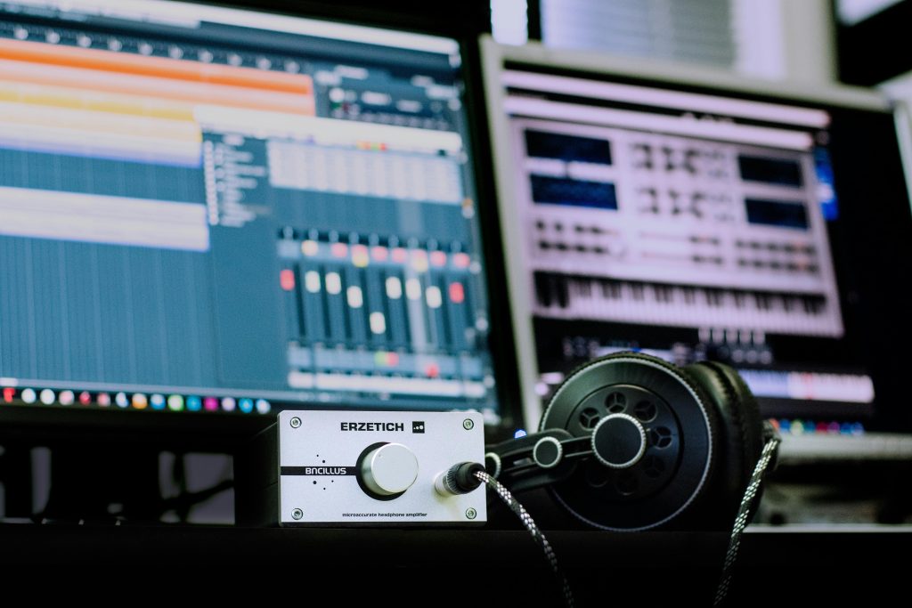 音樂編曲工作站前的耳機與聲音介面設備，搭配數位音樂軟體畫面