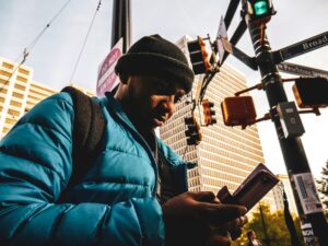 身穿藍色外套的男子站在亞特蘭大街頭，街景背景為城市高樓與交通號誌