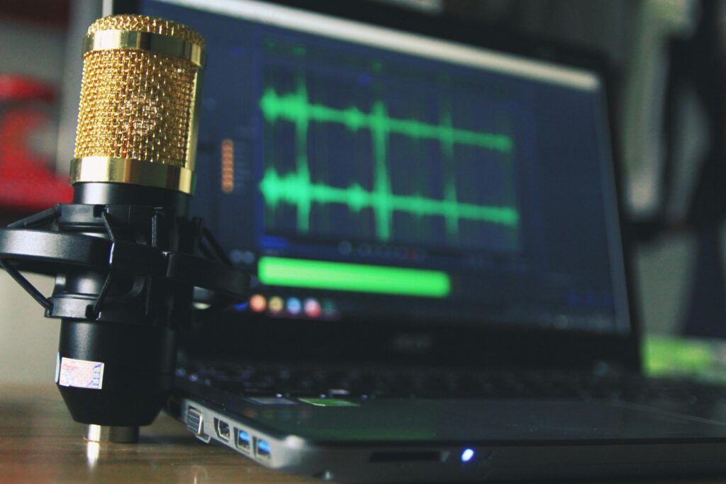 金色電容式麥克風與筆記型電腦音訊編輯畫面，專業音樂設備配置