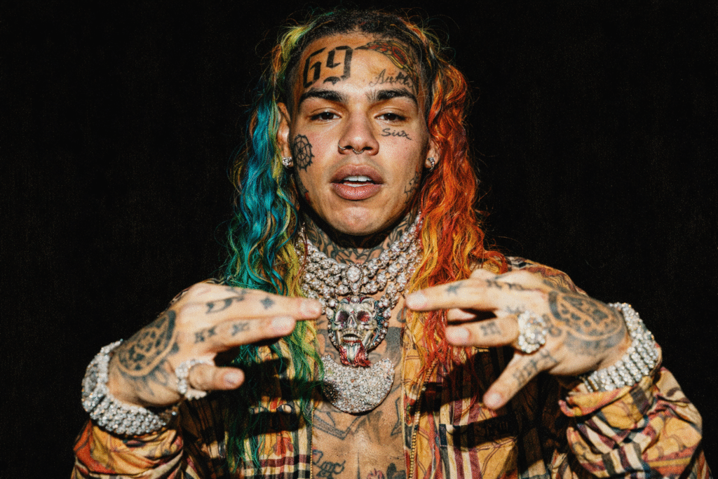 6ix9ine 近距離肖像，彩色長髮、臉部刺青與鑽石項鍊，展現極具爭議性的嘻哈形象