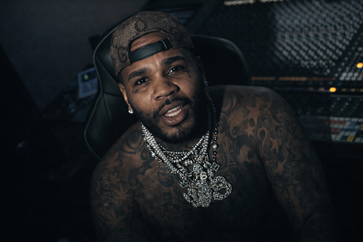 Kevin Gates 坐在錄音室內近距離肖像，赤裸上身配戴多層項鍊，呈現饒舌創作中的真實狀態與內在情緒