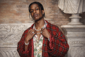 A$AP Rocky 身穿紅色格紋披肩與珍珠項鍊拍攝時尚形象照，展現高端品牌合作風格